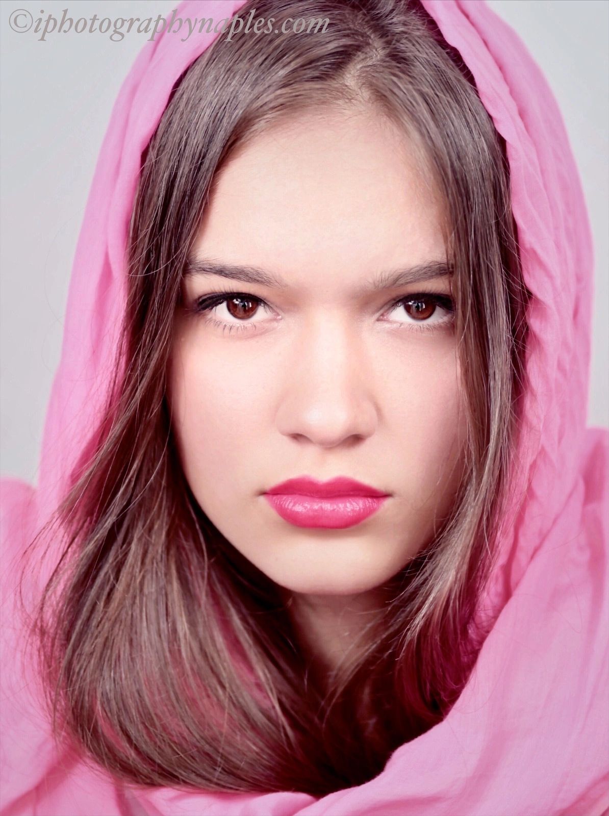Close-up portrait of a woman framed by pink fabric